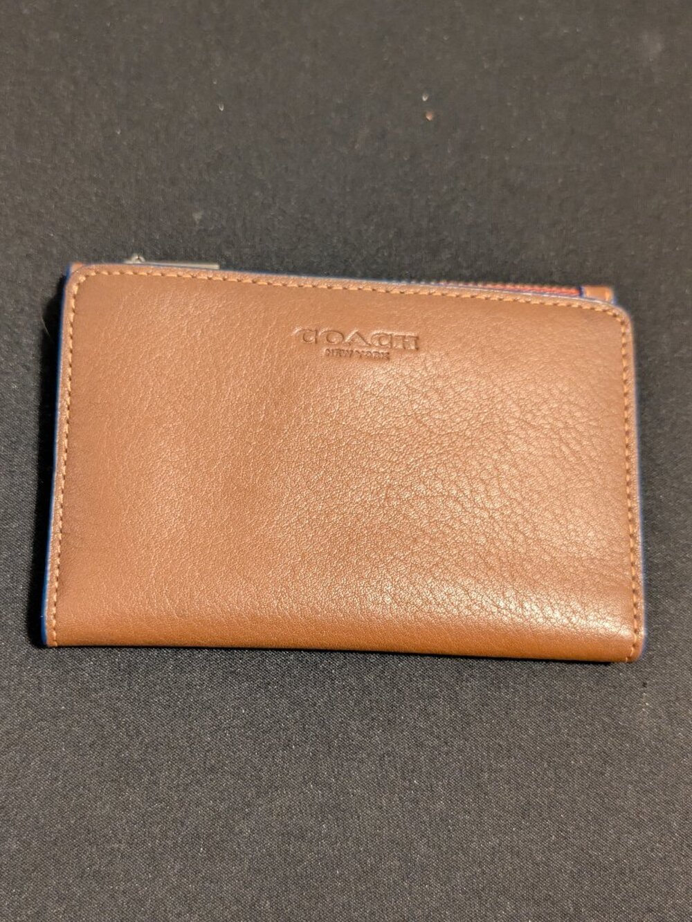 Coach zip card case featuring a embossed logo and blue edging